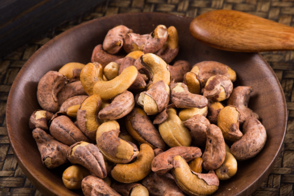 a bowl of cashews with a spoon