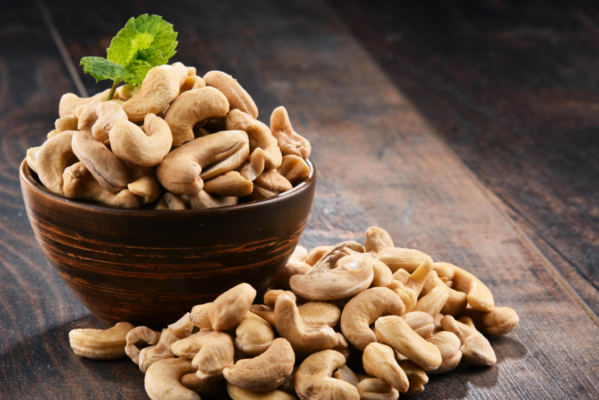 a bowl of cashew nuts with a leaf on top